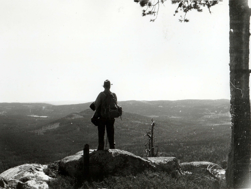 Finnskogen, Åsnes, Hedmark ca. 1957. Mann står på topp med utsikt.