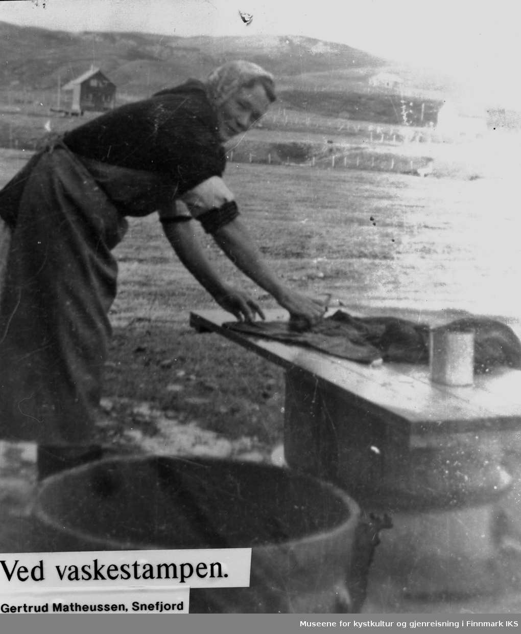 Kvinne vasker klær i stamp.