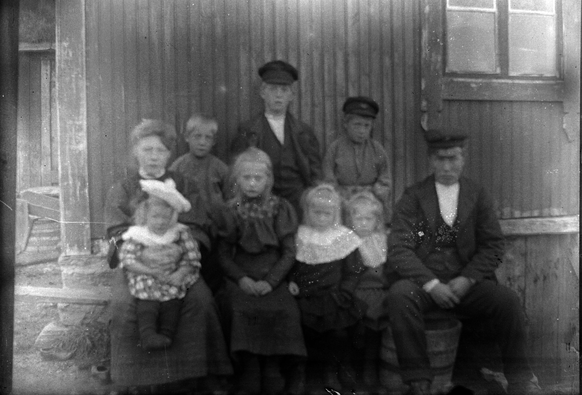 Gruppebilde av en mann og en kvinne med syv barn, foran en husvegg ...