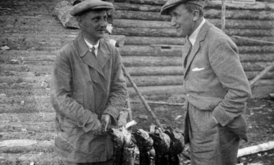 Egil Abrahamsen (1893-1977) og Frederik Prytz (1878-1945) fotografert med gjeddefangst i Arkhangelsk i Russland, der de begge var engasjert i russisk-norsk trelasthandel.  Fotografiet er åpenbart tatt i en fritidssituasjon.  Abrahamsen (til venstre) var kledd i ei slitt vindjakke og hadde sixpencelue på hodet.  Prytz hadde samme type hodeplagg, men ei grå dressjakke med kvitt lommetørklede i brystlomma. . Foto/Photo.