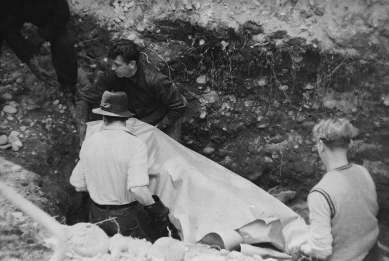 En båre tas opp fra massegravene av norske NS-medlemmer som ble beordret til arbeidet..