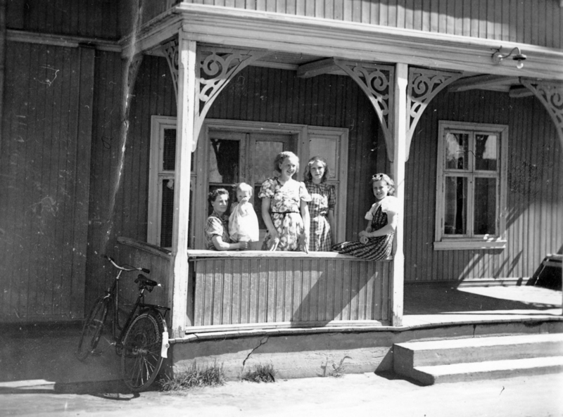 Gruppe barn og voksene samlet på verandaen til Hotel Køgler.