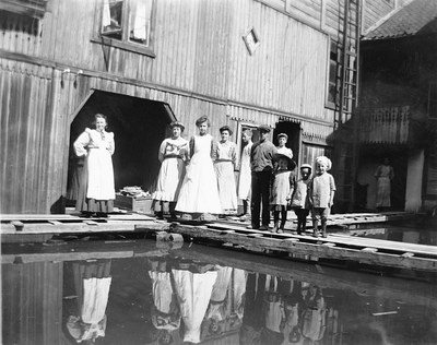 Folk i bakgården i Strandgata 15 i Hamar, hos baker Johannessen. Storflommen i 1927. Bakermesterfrue Lovise Johannessen til venstre. Foto/Photo.