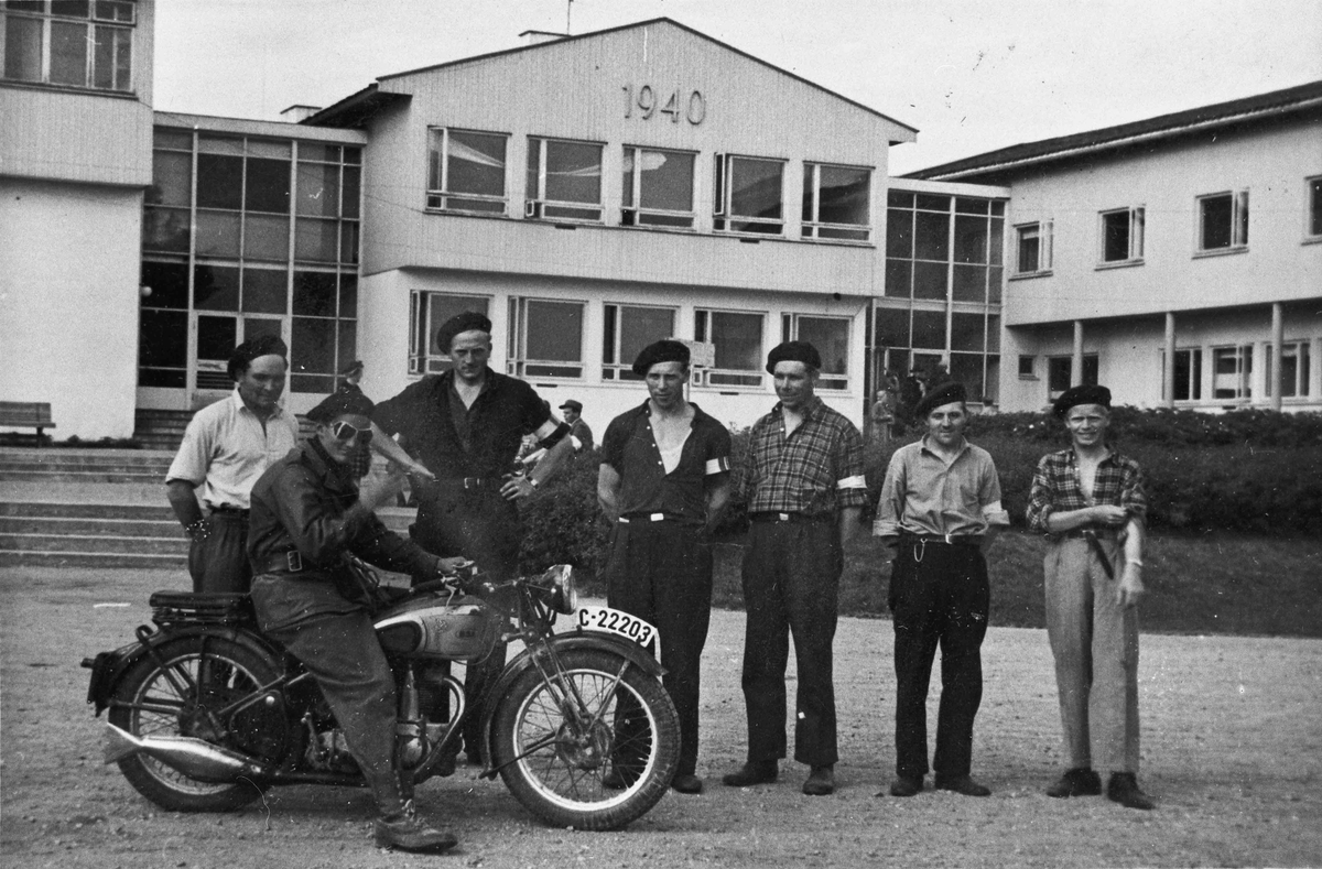 Hjemmestyrker utenfor Romerike Folkehøyskole. Motorsykkelen er en BSA – modell som kom i 1937.